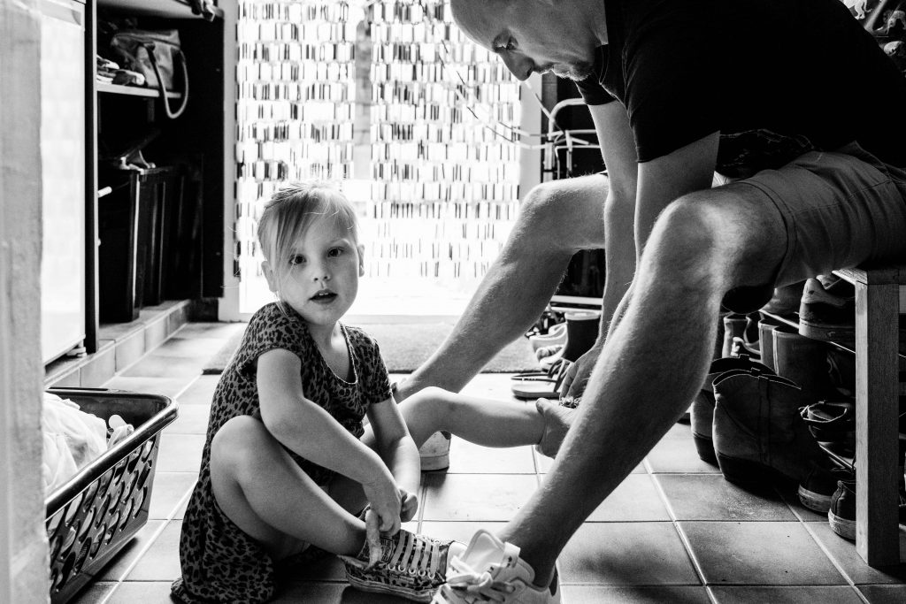 vader trekt schoenen bij dochter aan.